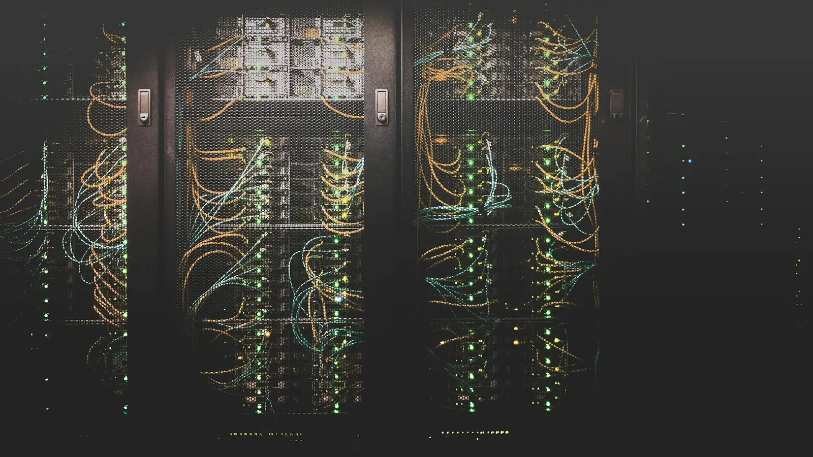 Baies de serveurs dans la pénombre d’un datacenter, câbles réseau et voyants d’activité allumés